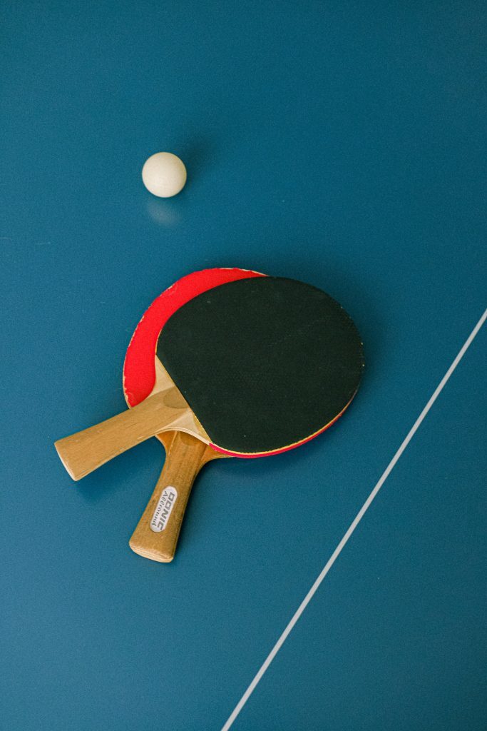 Two table tennis paddles and a ball on a table tennis table